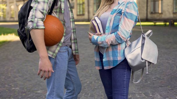 Young athletic man flirting with smart girl near university, students meeting - Foto, Imagen