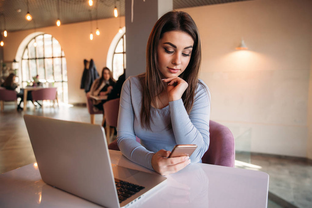 Femme d'affaires assise dans un café et travaillant sur un ordinateur portable et utilisant le téléphone
 - Photo, image