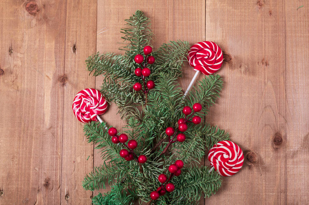 Christmas fir tree on wooden background. Red berries. Rustic style. Top view. Copy space. - Фото, изображение