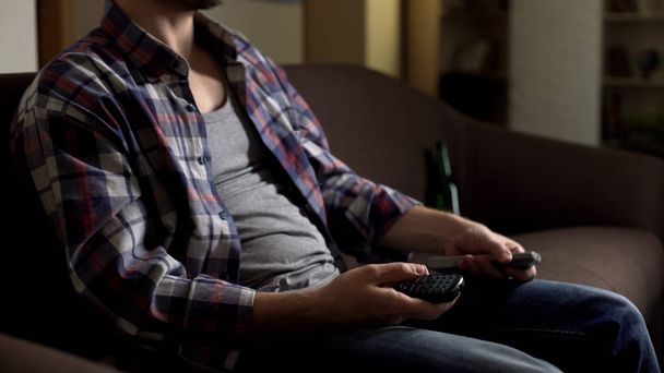 Bearded person switching buttons on remote control for TV set at home, relax - Φωτογραφία, εικόνα