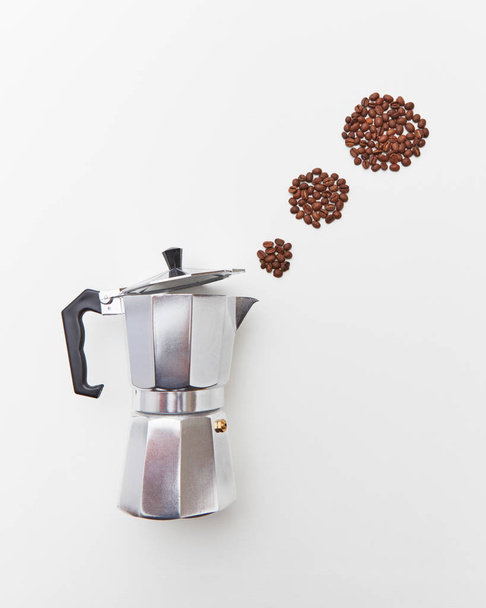 Circles of coffee beans in the form of a steam from a metal coffee maker on a white background copy space. The concept of making morning coffee. Flat lay - Photo, Image