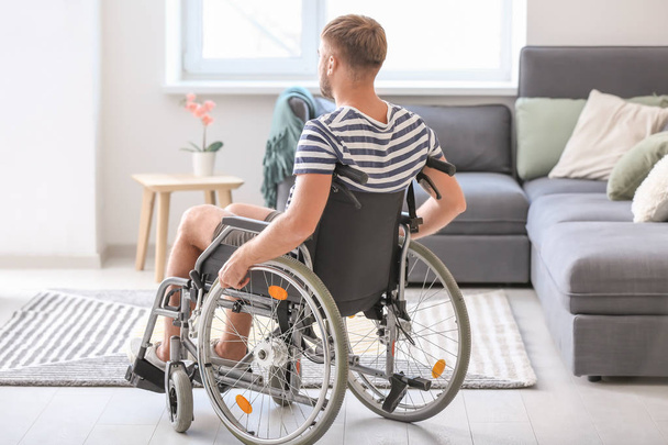 Młody człowiek na wózku inwalidzkim w domu - Zdjęcie, obraz