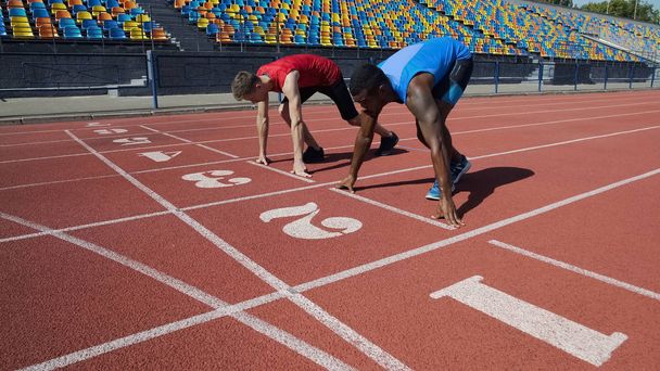 Multirassische Athleten in Startposition, bereit, nach Kommando zu laufen, Marathon - Foto, Bild