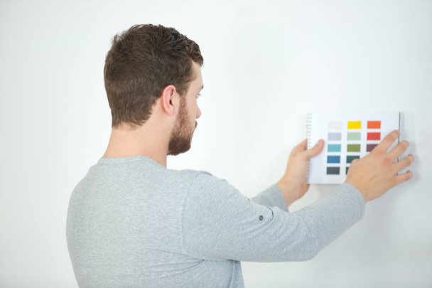 young man choosing color for walls to paint - Φωτογραφία, εικόνα