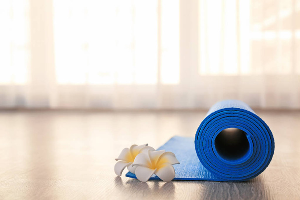 Stuoia rotolata di yoga e fiori sul pavimento
 - Foto, immagini