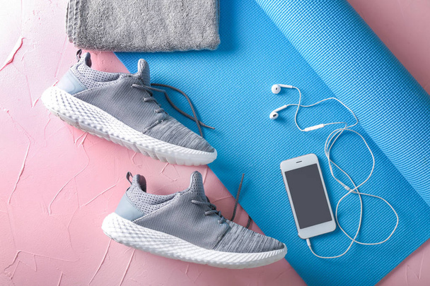 Yoga mat, sport shoes, towel and phone on color background - Photo, Image