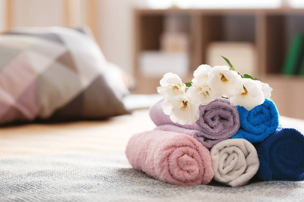 Warmgewalste schone handdoeken op bed - Foto, afbeelding
