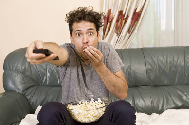 Man with beer and popcorn watching TV at home - Valokuva, kuva