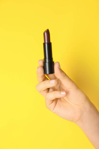 Woman holding dark lipstick on color background - Zdjęcie, obraz