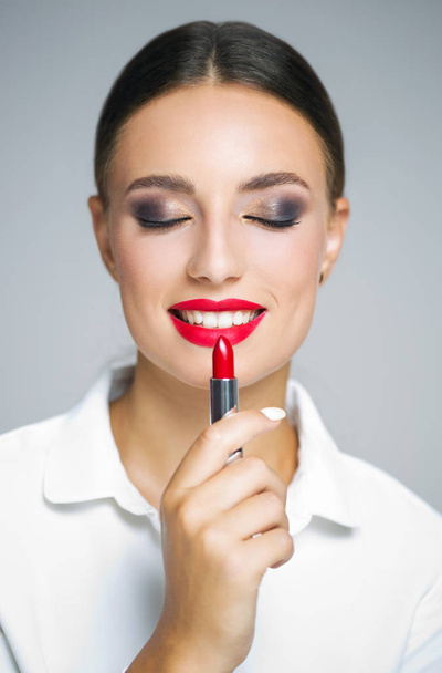Portrait of a young beautiful brunette  woman  in elegant makeup with striking red lips. - Zdjęcie, obraz