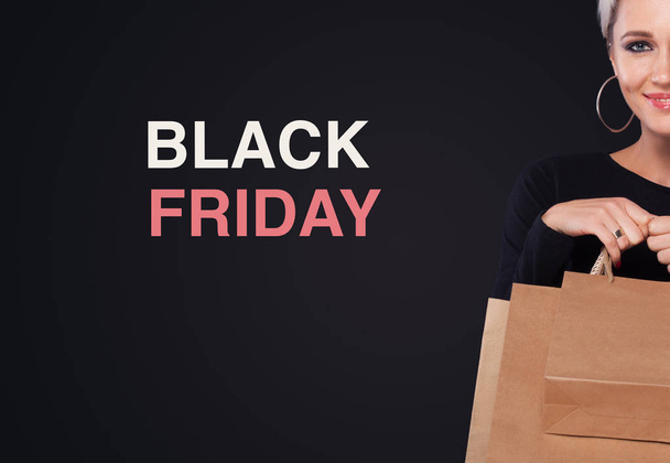 Shopping femme tenant des sacs d'artisanat isolé sur fond noir avec copyspace en vacances noir vendredi. Concept de vente Black Friday
. - Photo, image