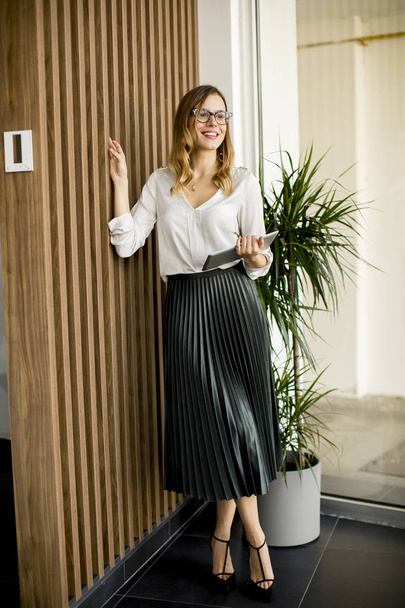 Portret młodego bizneswoman z cyfrowego tabletu przez ściany w nowoczesnym biurze - Zdjęcie, obraz