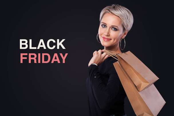 黒い金曜日休日の copyspace と黒の背景に分離されたクラフト袋を保持している女性をショッピングします。黒い金曜日販売コンセプト. - 写真・画像