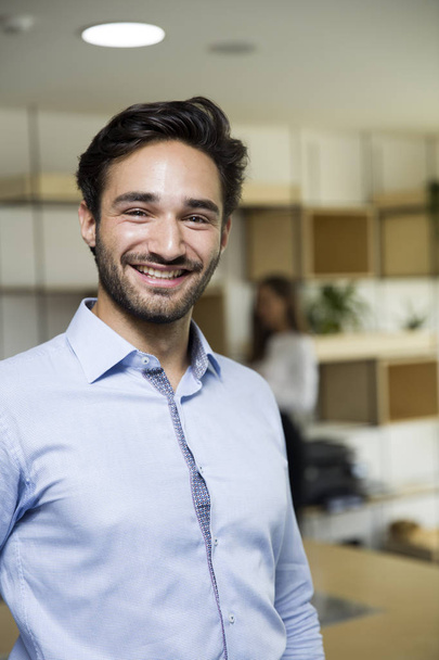 Πορτρέτο του χαρούμενος νεαρός επιχειρηματίας χαμογελά στο γραφείο - Φωτογραφία, εικόνα