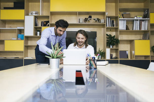 Δύο νέοι επιχειρηματίες που εργάζονται στο lap-top στο γραφείο - Φωτογραφία, εικόνα