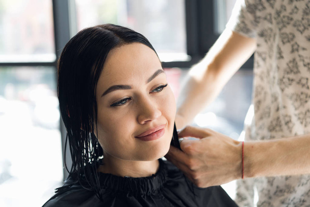 Парикмахер делает стрижку с ножницами волос молодой девушке в салоне красоты
. - Фото, изображение