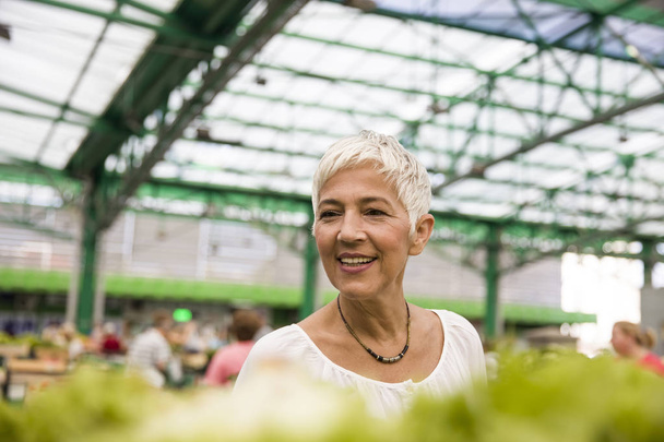 Портрет літньої жінки, що купує свіжий органічний овоч на ринку
 - Фото, зображення