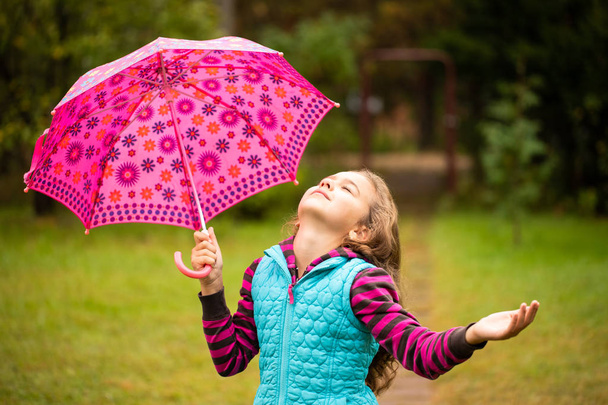 Gyönyörű bájos orosz lány szeme zárt tart a kezében, színes mintás esernyő séta, élvezve őszi természet Park közelről. - Fotó, kép