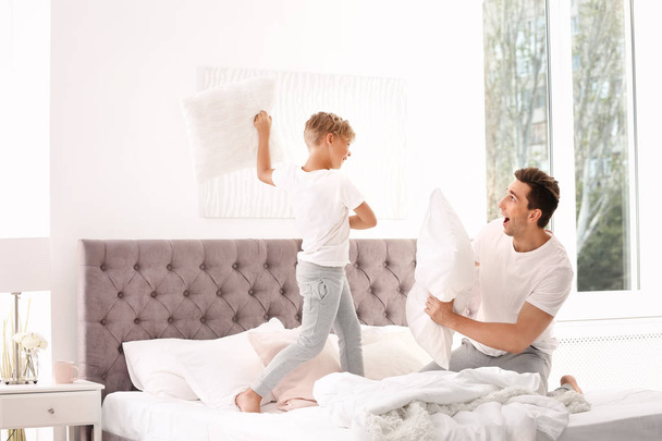 Father and son having pillow fight on bed at home - Fotografie, Obrázek