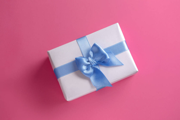 Gift box with blue ribbon on color background - Photo, Image