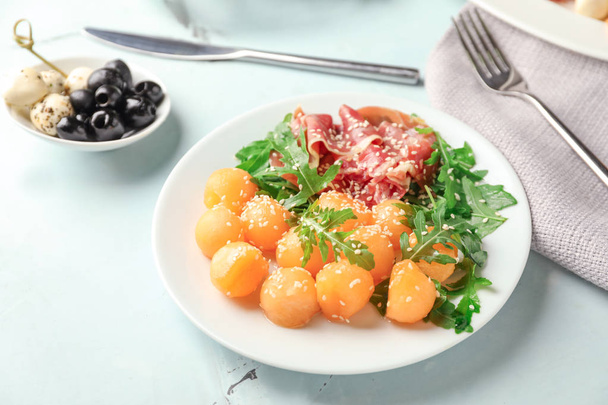 Plate with delicious melon balls and prosciutto on table - Foto, Imagen