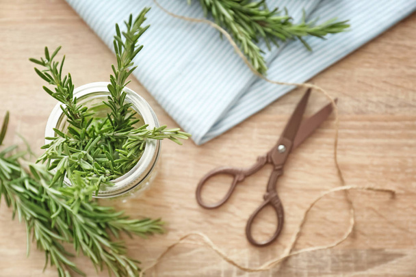 Glass jar with fresh rosemary on wooden table, top view - Valokuva, kuva