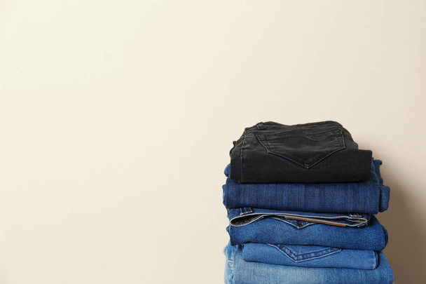 Stack of different jeans against light background - Фото, изображение