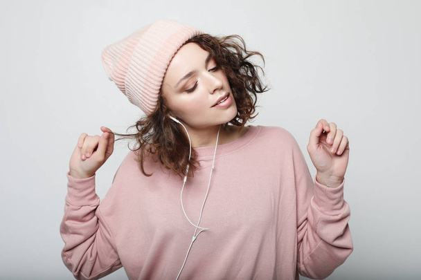 lifestyle and people concept: Beautiful young curly woman in headphones listening to music smiling with closed eyes - Photo, Image