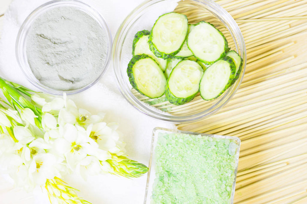Cucumber home spa and hair care concept. Sliced cucumber, bottles of oil, sea salt, bathroom towel. Straw light background. Closeup - Φωτογραφία, εικόνα