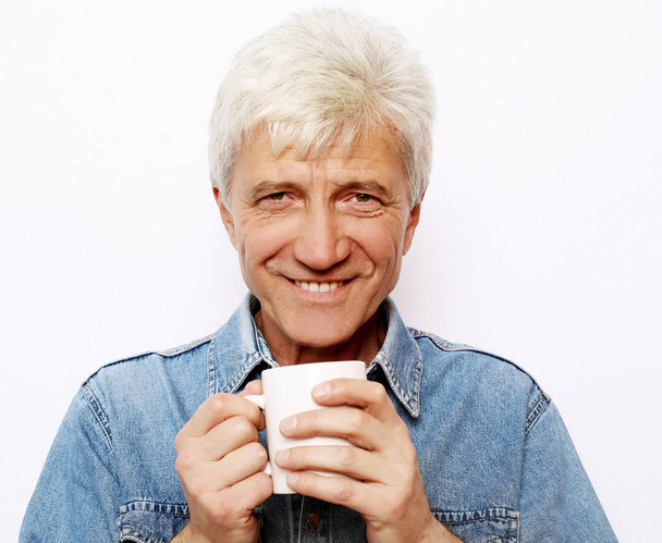 lifestyle, food and people concept: Handsome mature man hoding a cup of coffee or tea - Valokuva, kuva
