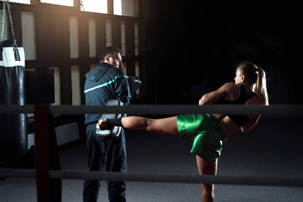 Młody dorosły kobieta robi kopnięcie podczas treningu kickboxingu - Zdjęcie, obraz