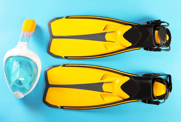Pair of yellow flippers and diving mask on color background, top view - Foto, Imagen
