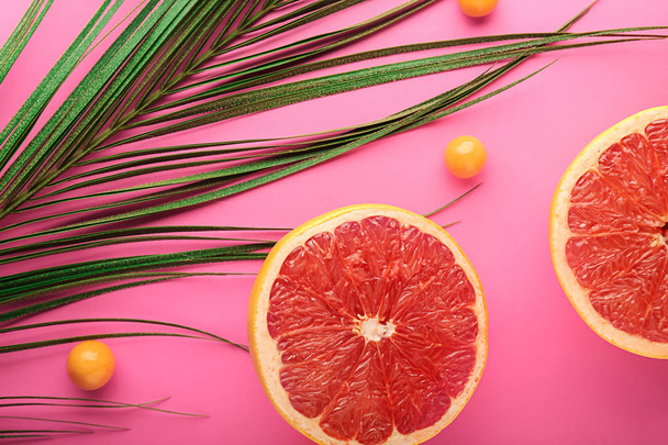 Кусочки спелого сочного грейпфрута и пальмового листа на цветном фоне
 - Фото, изображение