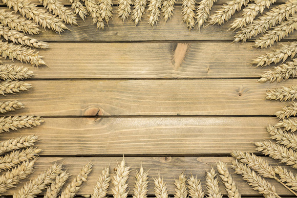 Wheat or rye spikelets on wooden background - Foto, afbeelding