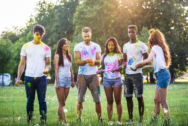 Groep gelukkige vrienden spelen met holi kleuren in een park - jonge volwassenen plezier op een festival van holi, basisbegrippen door over het leuk, geweldig leuke en jonge generatie - Foto, afbeelding