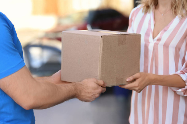 Woman receiving parcel from deliveryman on blurred background, closeup. Space for text - Фото, зображення