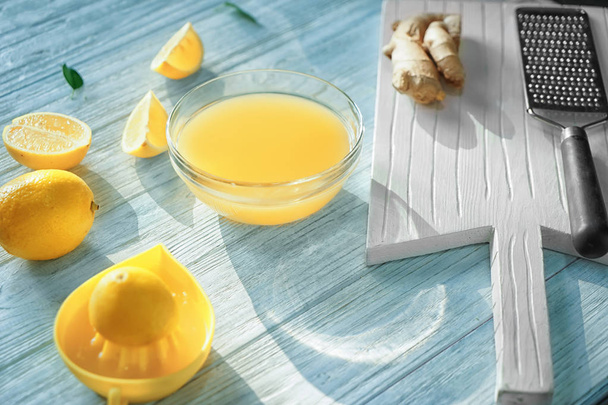 Renk ahşap masa üzerinde taze sıkılmış limon suyu ile cam kase - Fotoğraf, Görsel