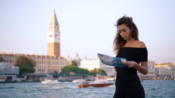Attractive young woman traveling in Europe and exploring beautiful sightseeing in Barcelona, sunshine lens flare, slow motion, hipster girl wearing glasses and holding tourist map, enjoying holiday - Footage, Video