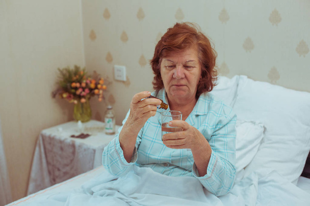 Lonelly senior mujer bebiendo medecina
. - Foto, Imagen