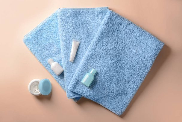 Clean soft towels with cosmetics on color background - Photo, image