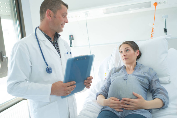 Arzt spricht mit schwangerer Frau - Foto, Bild