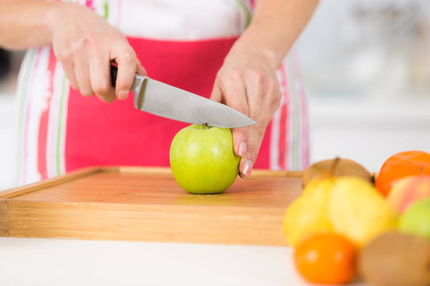 close-up on mature female hands slicing apples on chopping board - Photo, image