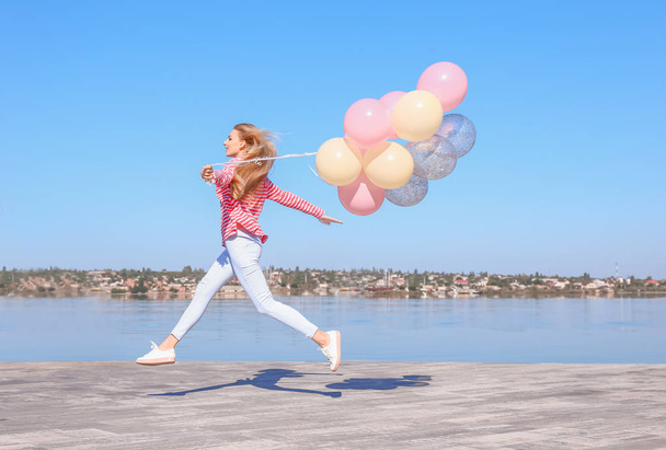 Hermosa joven con globos de aire cerca del río
 - Foto, imagen