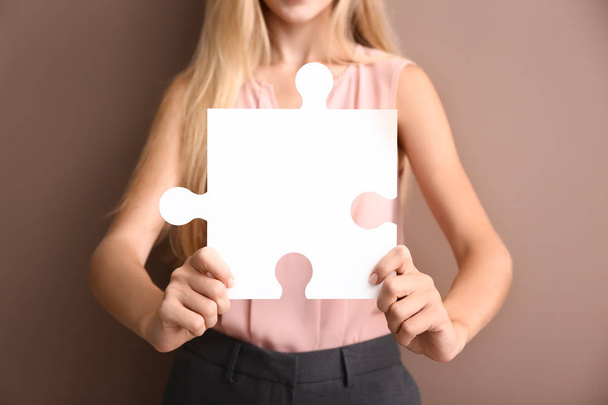 Young woman with piece of puzzle on color background - Photo, Image