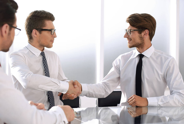 business partners shake hands while sitting at the Desk - Fotó, kép