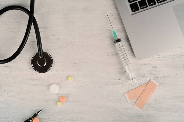 Vista dall'alto di laptop, stetoscopio e pillole alla scrivania del medico. Medicina moderna sul posto di lavoro
 - Foto, immagini