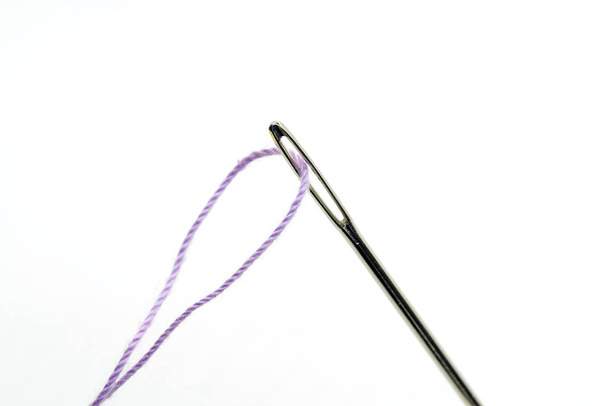Aguja de metal aislada con un hilo púrpura
 - Foto, imagen