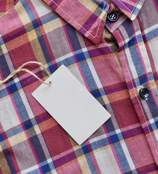 Красная, синяя, белая клетчатая рубашка и этикетка одежды
 - Фото, изображение