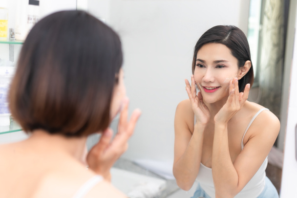 Kadın mutlu lavabo üzerinde köpük ile cildi temizler. - Fotoğraf, Görsel