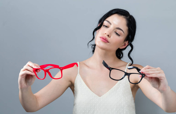 Young woman comparing two eye glasses - Fotoğraf, Görsel